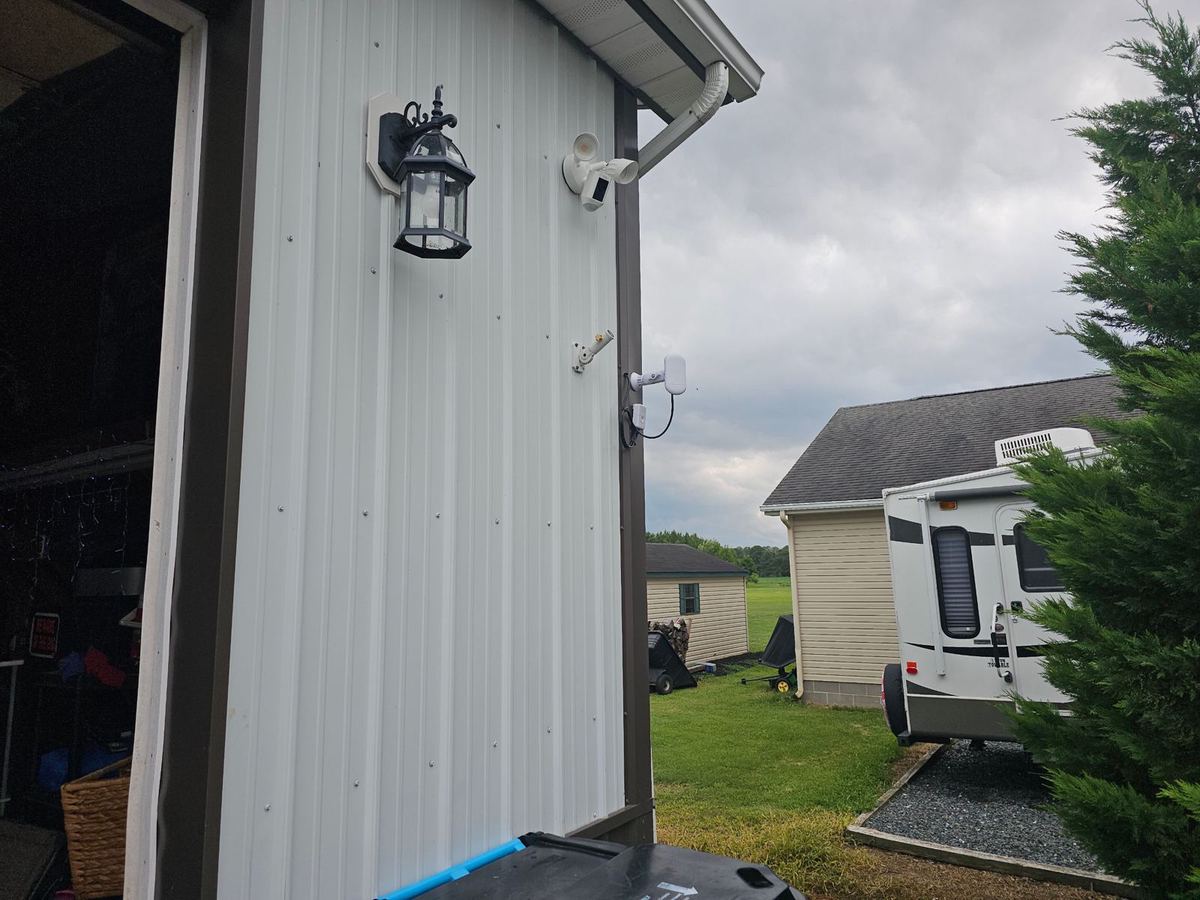 Outbuilding with a wireless bridge radio and floodlight camera mounted on the siding
