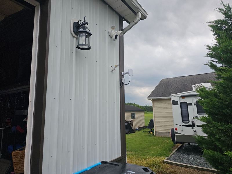 Outbuilding with a wireless bridge radio and floodlight camera mounted on the siding